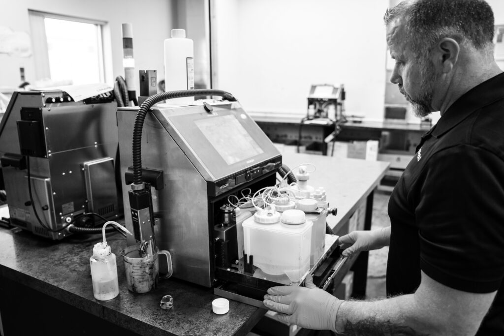 Black and white image of a MarkPack employee servicing a Hitachi machine